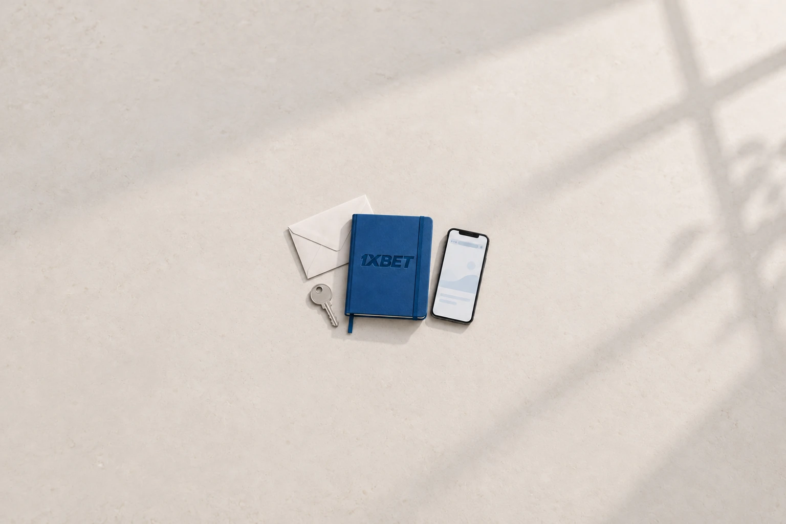 Une clé, une enveloppe et un téléphone entourent un carnet de récupération bleu 1XBET.